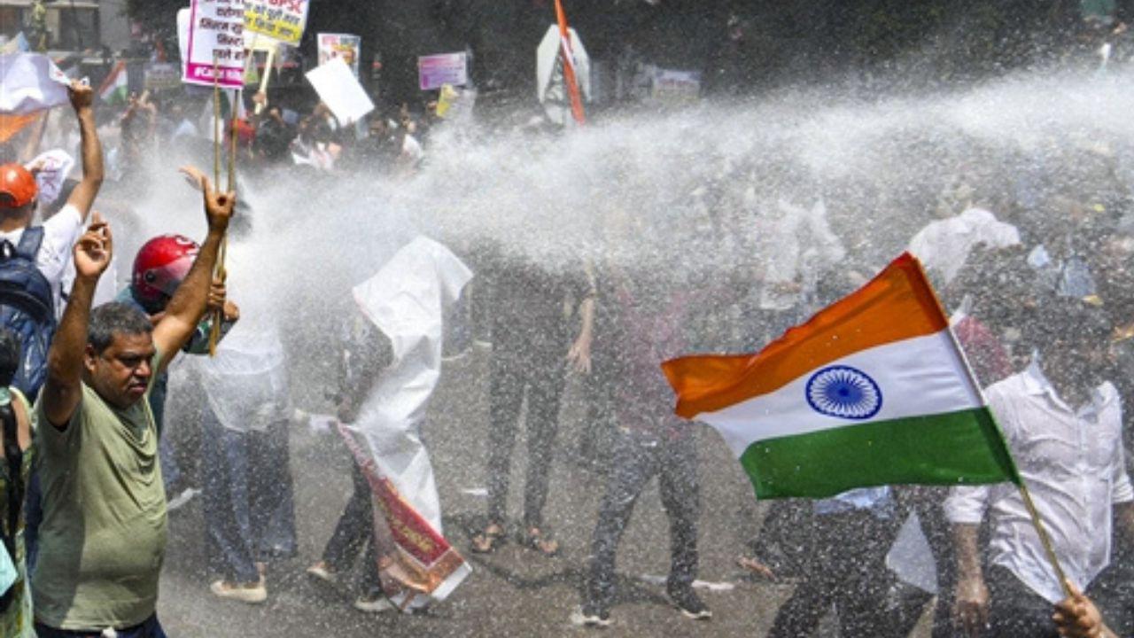 Police personnel using water cannons to disperse protesting students during a demonstration in Patna. Students and other protesters are seen gathered on the road as a powerful stream of water is directed towards the crowd amid the ongoing protest.